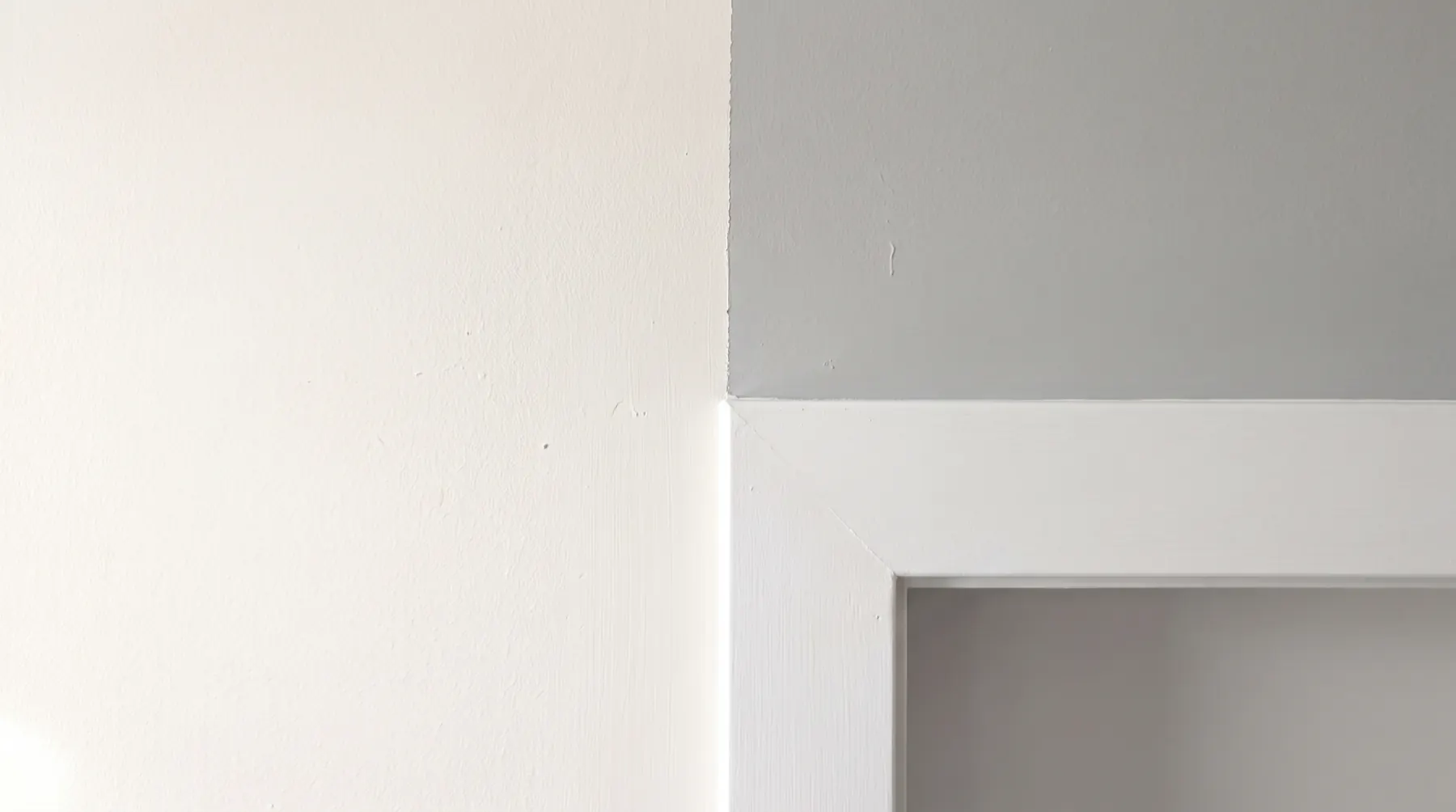 A crisp painted line where a warm white wall meets grey and white door casing
