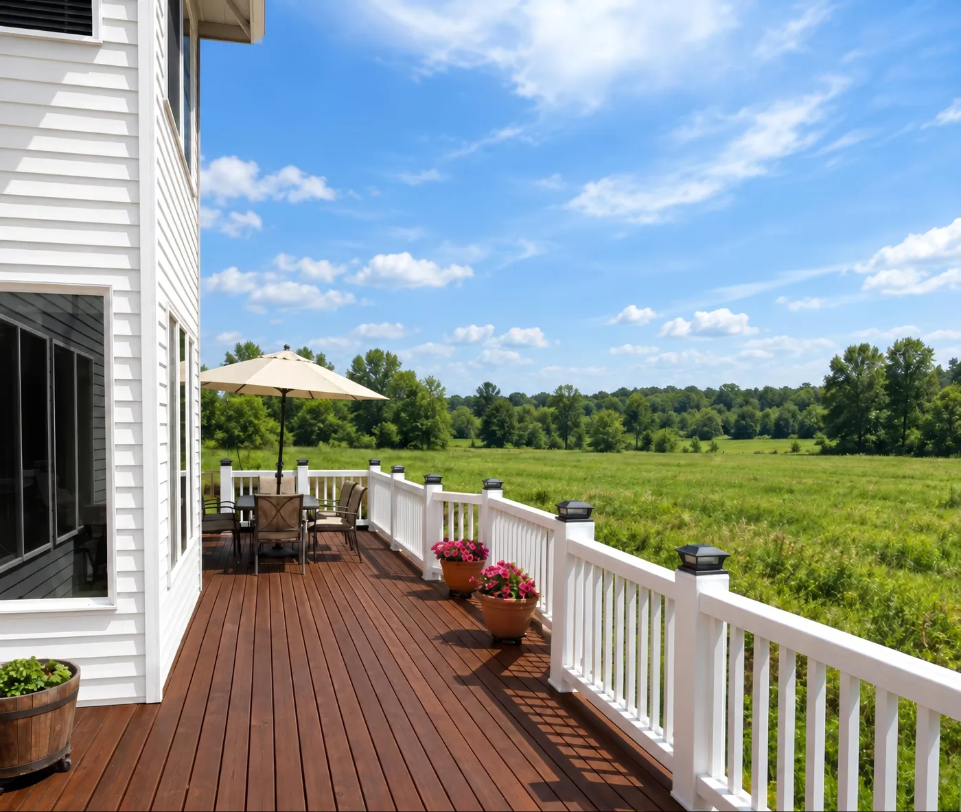 A stained wood deck with white railings along a white-sided house