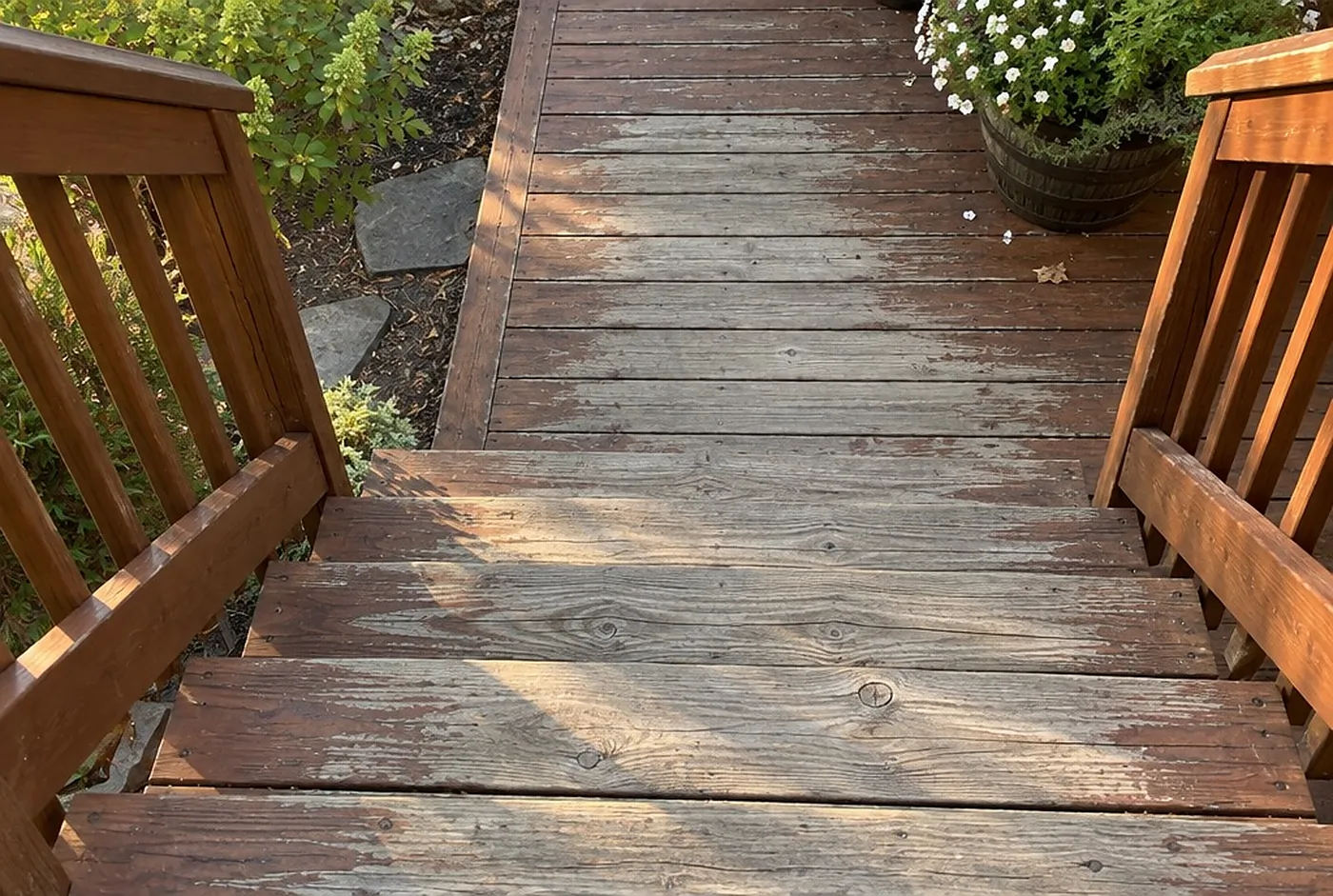 A deck with stain worn off the walking paths but still showing at the edges