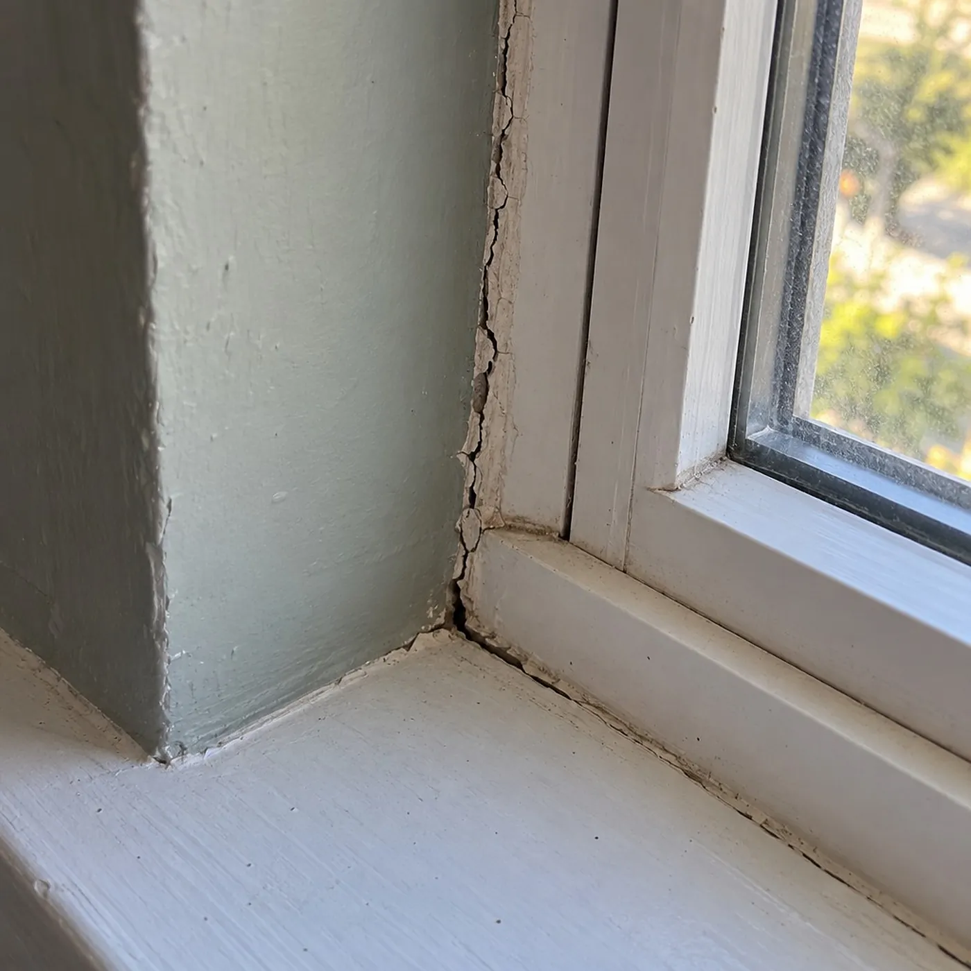 Cracked, gapped caulk at the corner of a window frame