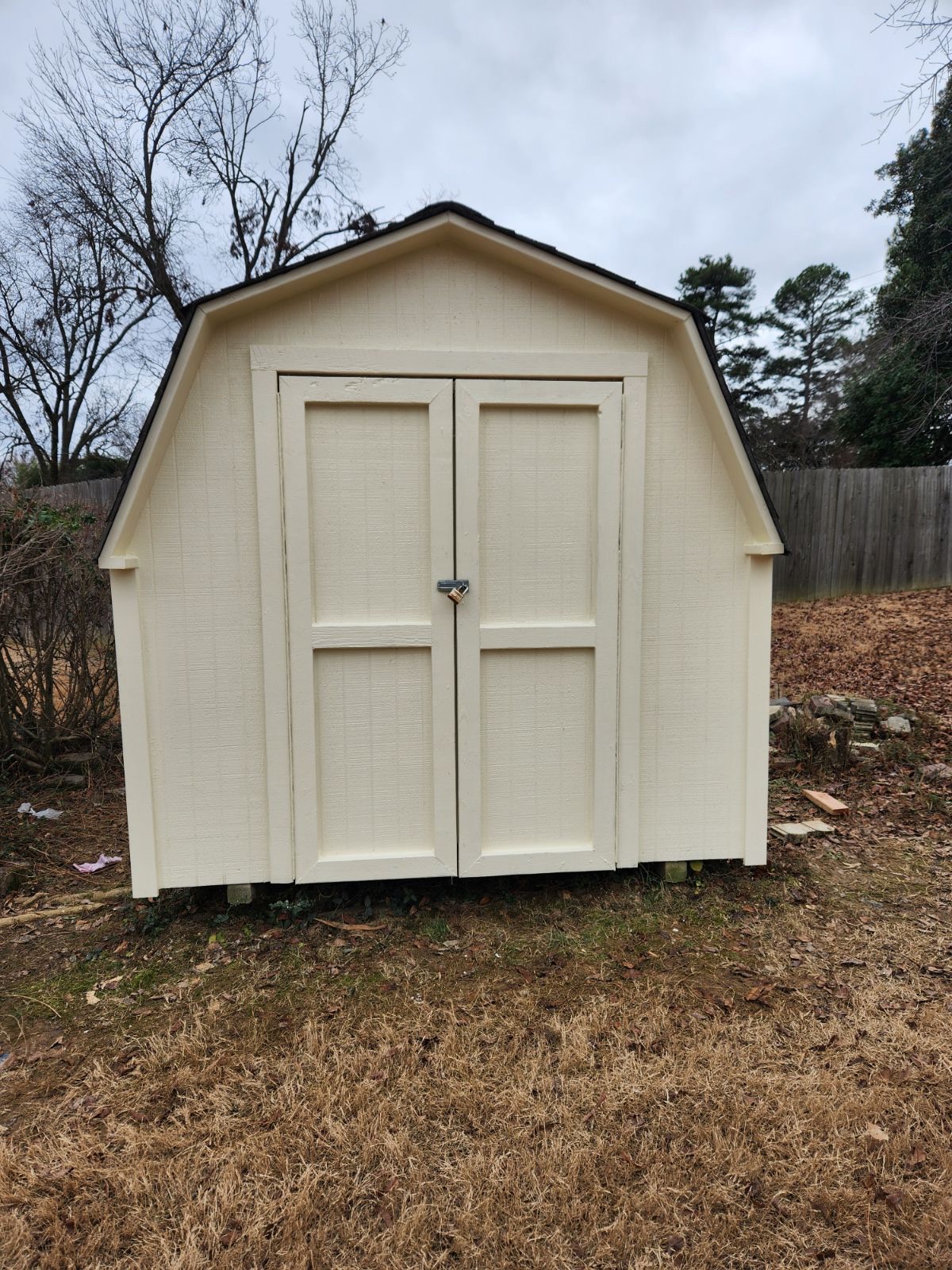 Same backyard shed after being primed and painted cream with black trim