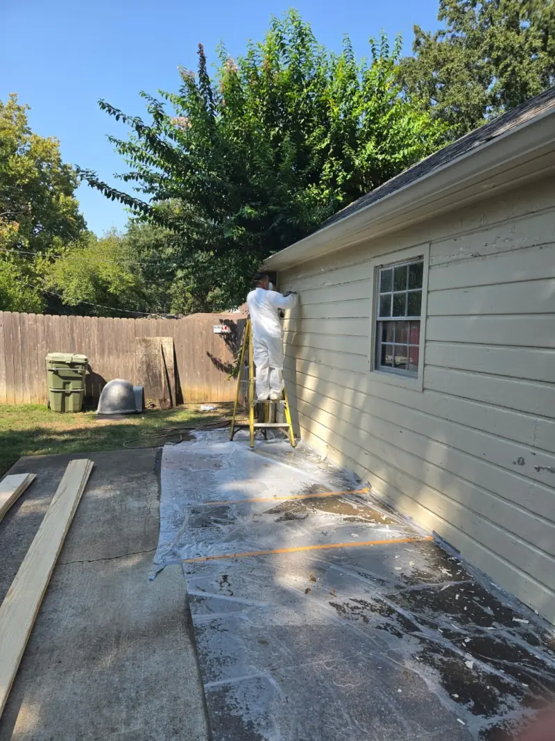 House siding scraped before painting, with paint chips on the ground